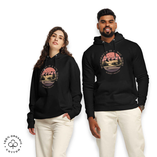 Woman and Men wearing black organic cotton hoodie with nature-themed graphic, mountain, forest, sun and river. With bold Wilderness is a way home, where I belong.