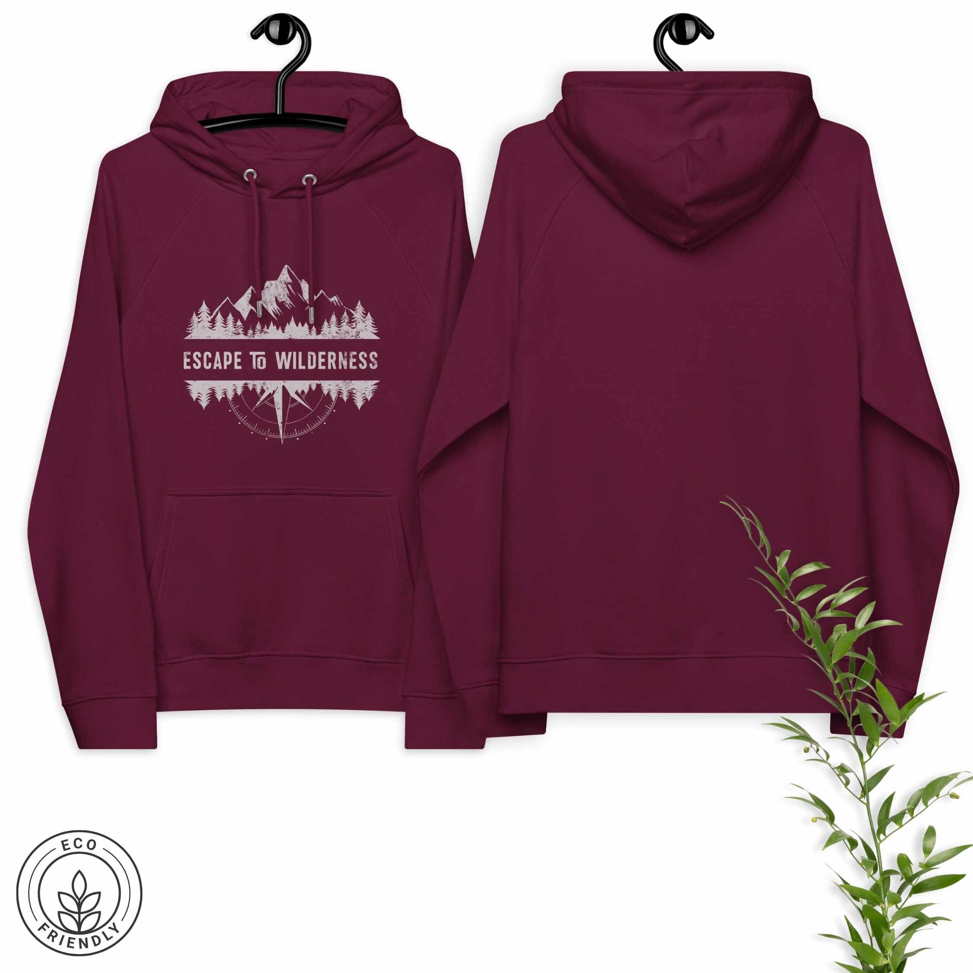 Burgundy eco-friendly hoodie featuring forrest, mountain and compass and  'Escape to Wilderness' graphic text on a hanger against a white background.