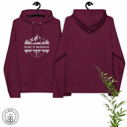 Burgundy eco-friendly hoodie featuring forrest, mountain and compass and  'Escape to Wilderness' graphic text on a hanger against a white background.