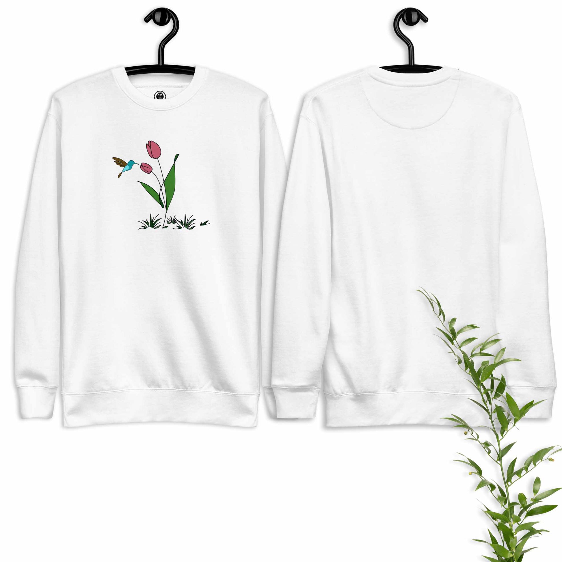 White sweatshirt with floral design featuring tulips and a hummingbird on a hanger against a white background