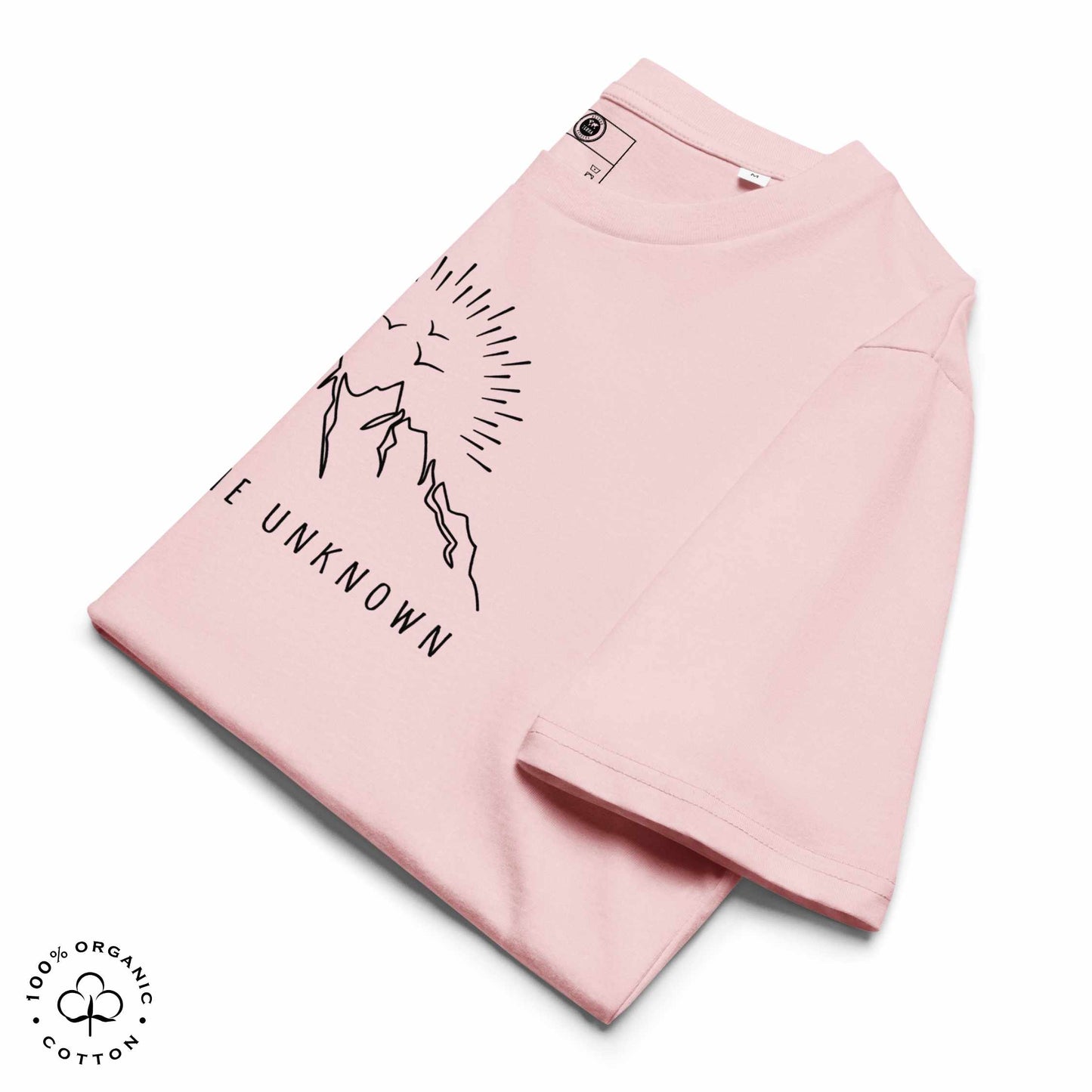 folded Pink organic cotton t-shirt with mountain, sun and birds graphic and 'Explore the Unknown' text  on a white background