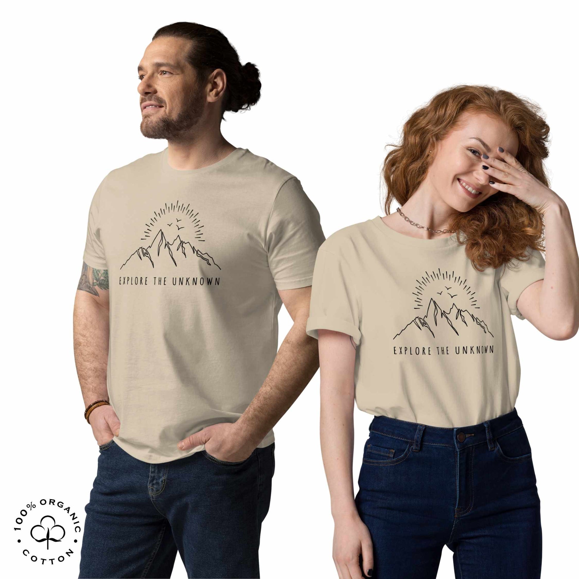 happy Man and woman wearing desert organic cotton t-shirt with mountain, sun and birds graphic and 'Explore the Unknown' text on a white background.