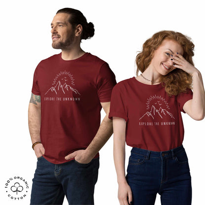 Happy man and woman wearing Burgundy organic cotton t-shirt with mountain, sun and birds graphic and 'Explore the Unknown' text  on a white background.