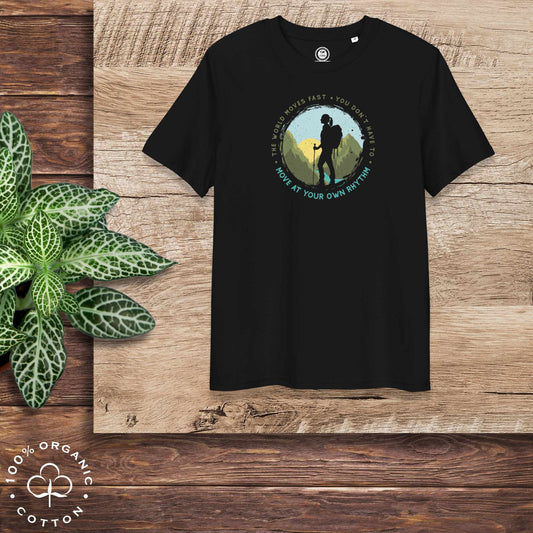 T-shirt with a hiking graphic on a wooden surface with bold "The world moves fast. You don't have to. Move at your own rhythm". 