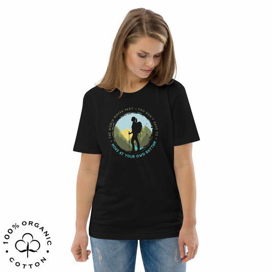 T-shirt with a hiking graphic on a wooden surface with bold "The world moves fast. You don't have to. Move at your own rhythm". 