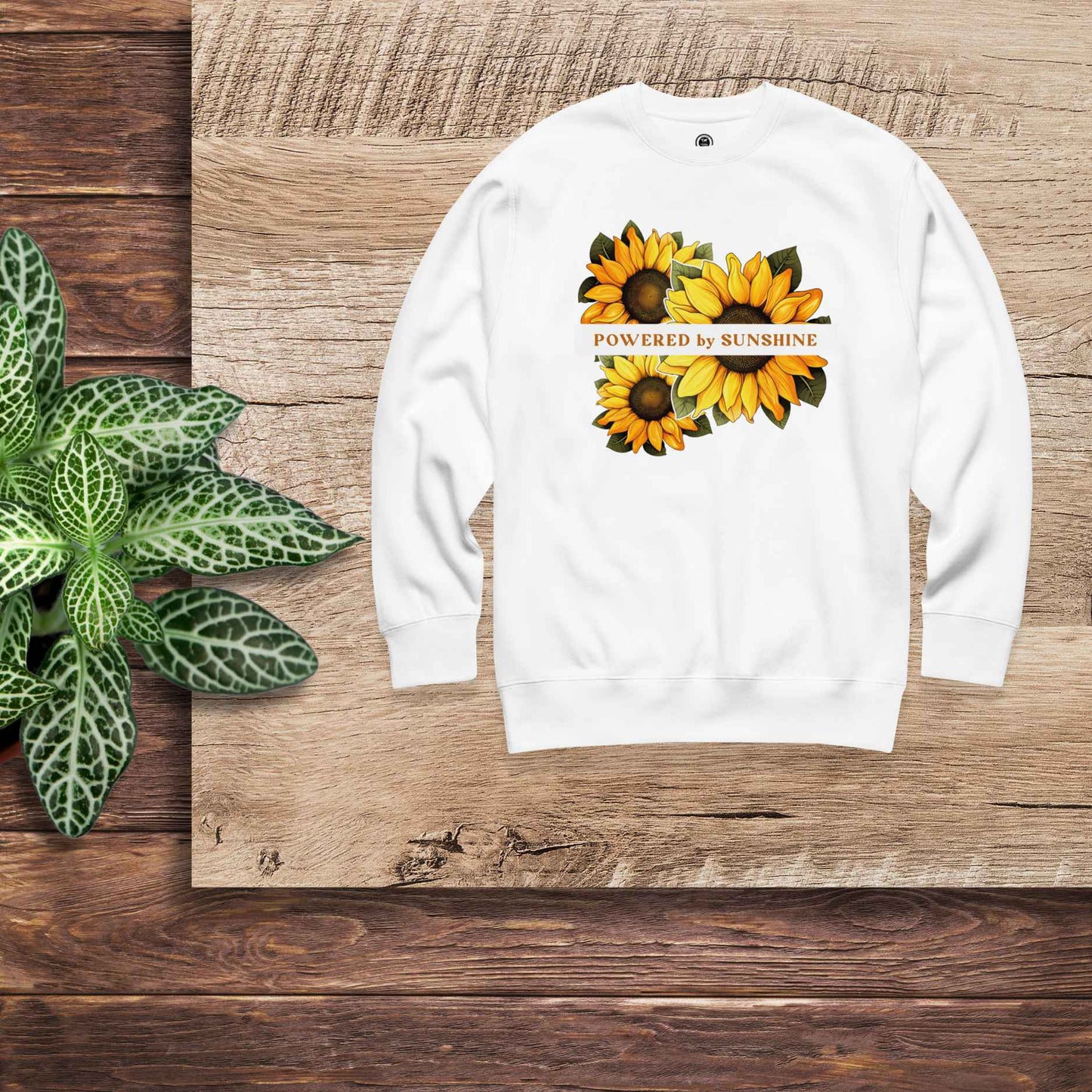 Woman sweatshirt with sunflower design and text Powered by Sunshine.