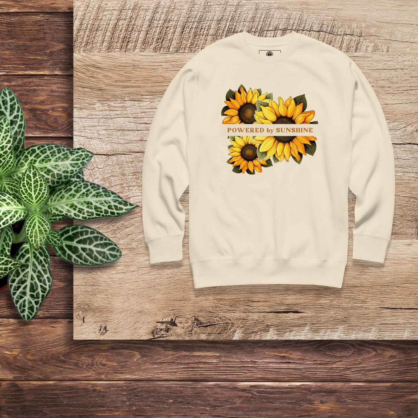 Woman sweatshirt with sunflower design and text Powered by Sunshine.