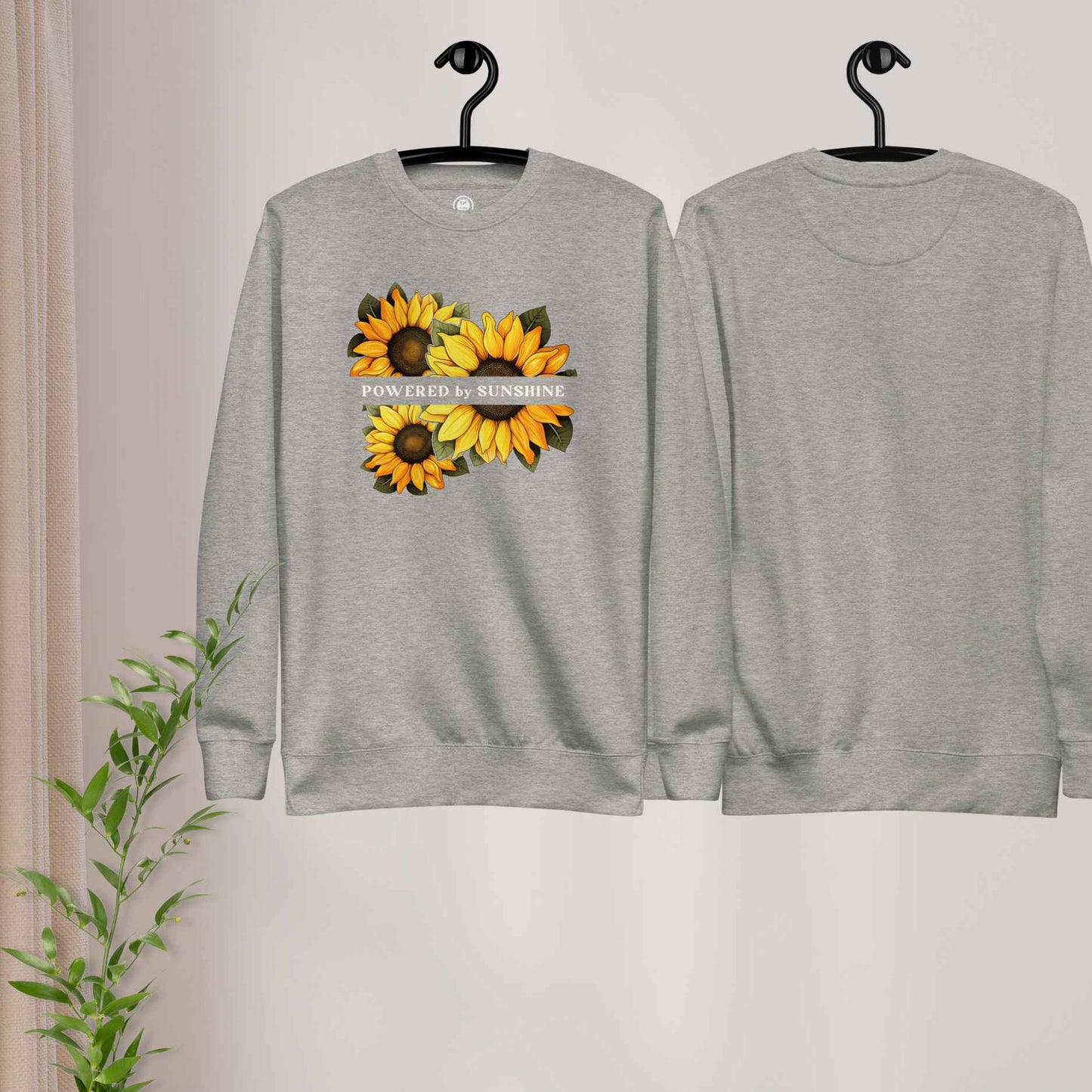 Woman sweatshirt with sunflower design and text Powered by Sunshine.