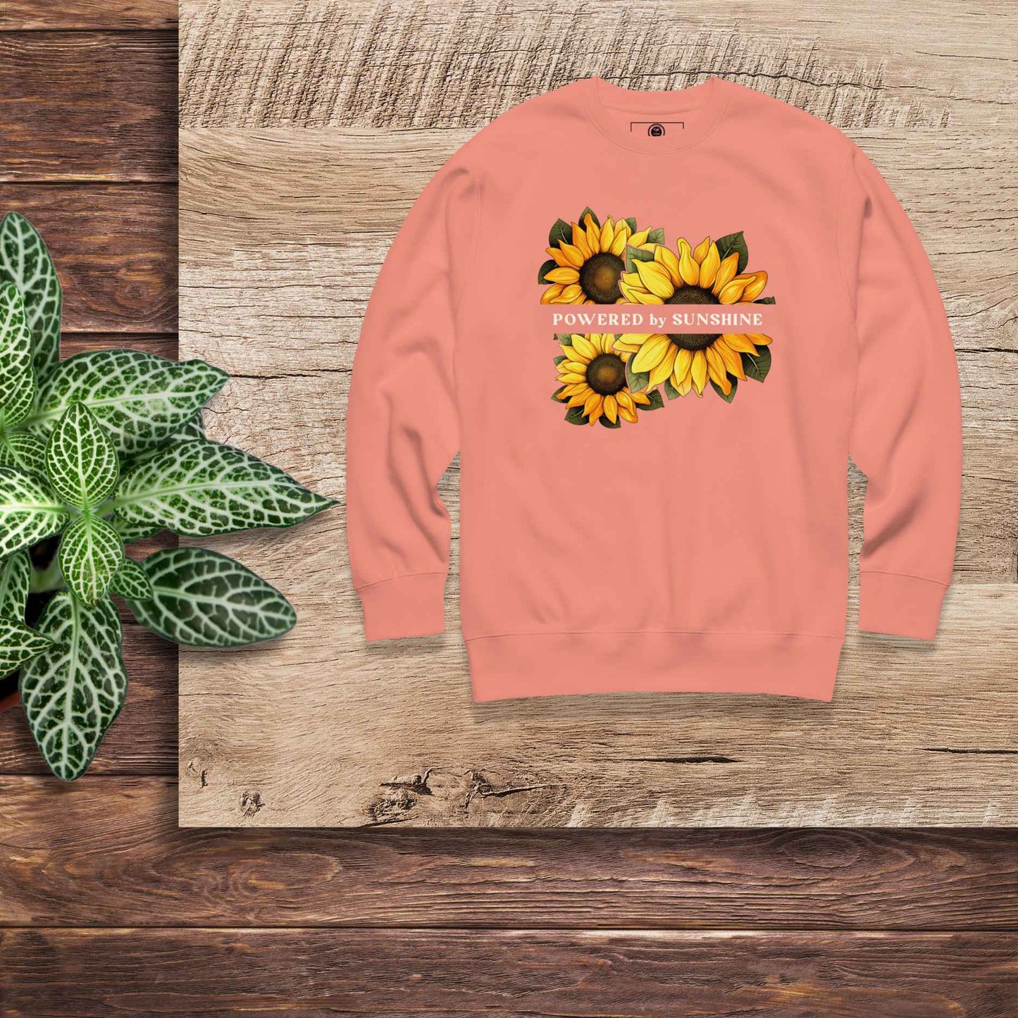 Woman sweatshirt with sunflower design and text Powered by Sunshine.