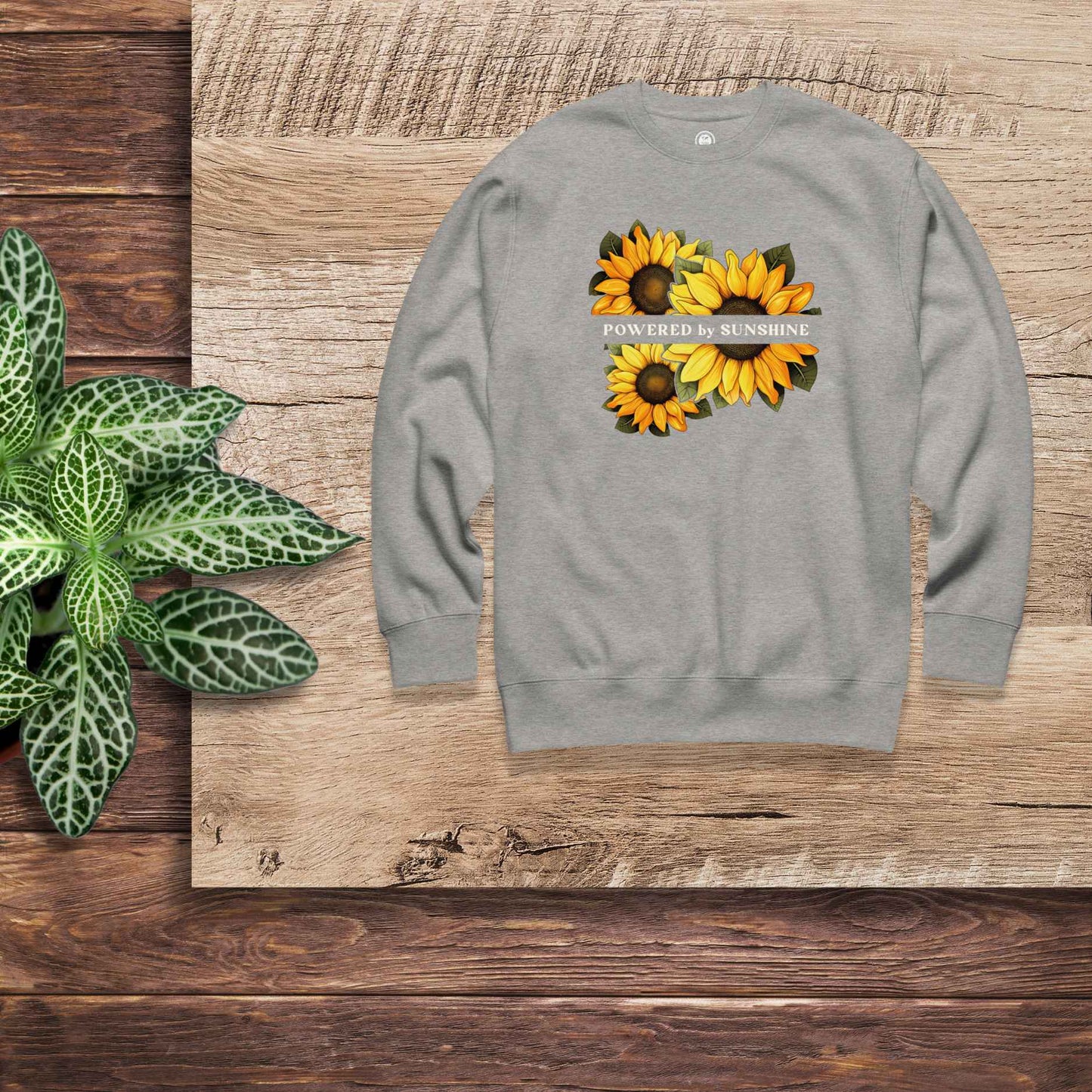 Woman sweatshirt with sunflower design and text Powered by Sunshine.