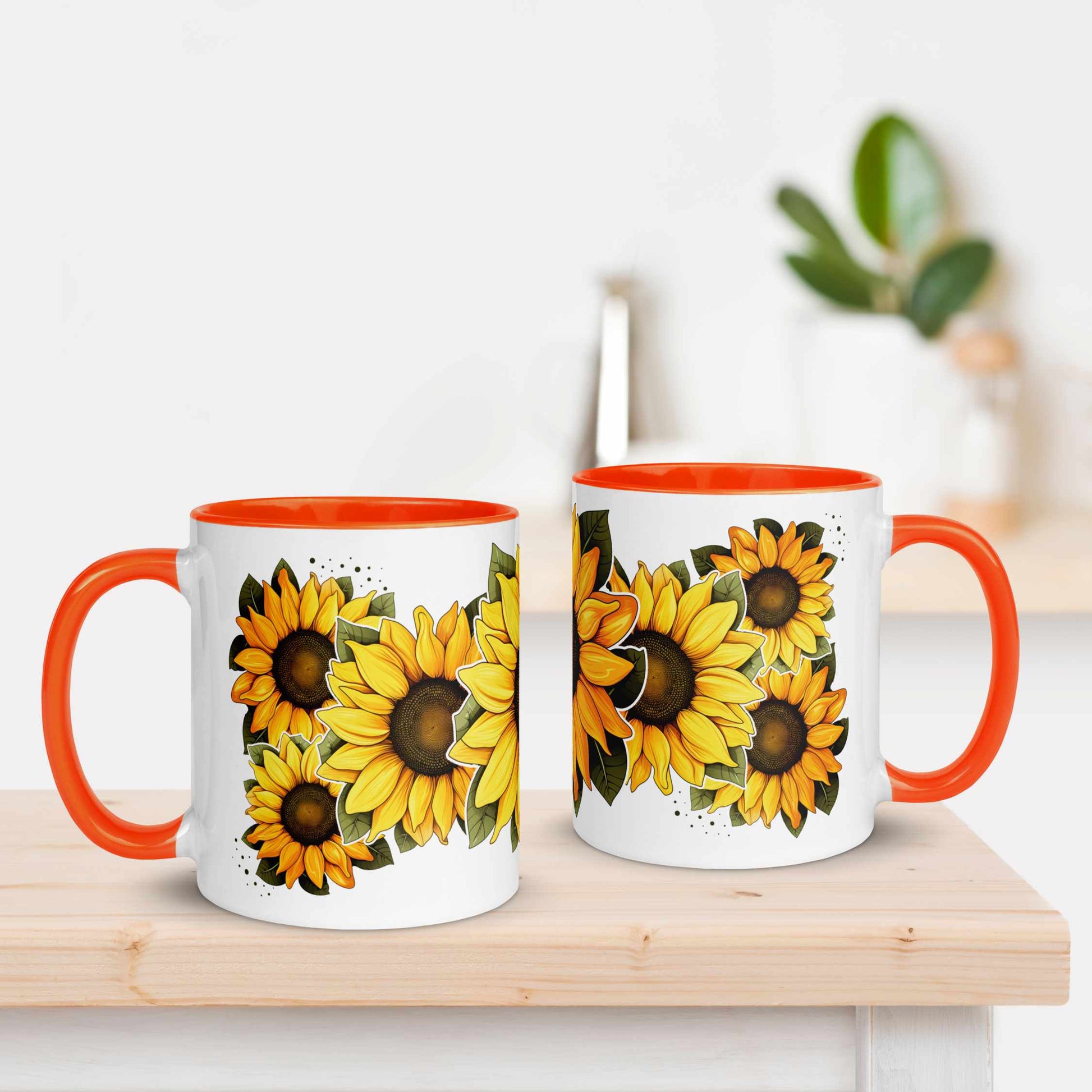 Two mugs with sunflower design and orange handles on a wooden surface.