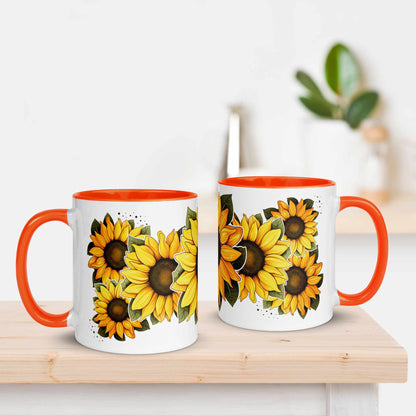 Two mugs with sunflower design and orange handles on a wooden surface.