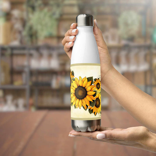 Person holding a water bottle stainless steel with sunflower design in a blurred indoor setting