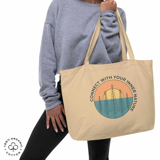 Woman holding oyster organic cotton tote bag with nature-themed design featuring sun and trees and 'Connect with Your Inner Nature' text on a white background.