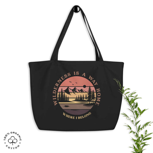 Black organic cotton large tote bag with nature-themed design: forest, trees, sun, lake. 'Wilderness is a Way Home, Where I belong' text. 