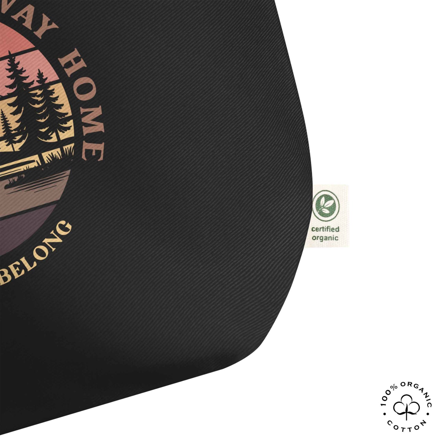 Close-up black organic cotton large tote bag with nature-themed design: forest, trees, sun, lake. 'Wilderness is a Way Home, Where I belong' text. 