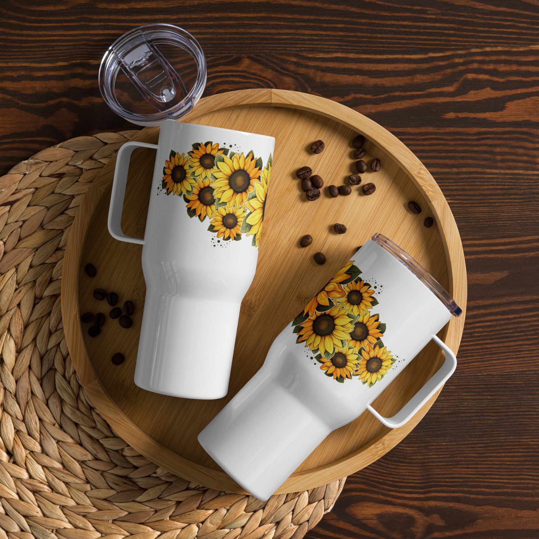 Two white insulated travel mugs 25 oz with sunflower designs on a wooden tray with coffee beans.