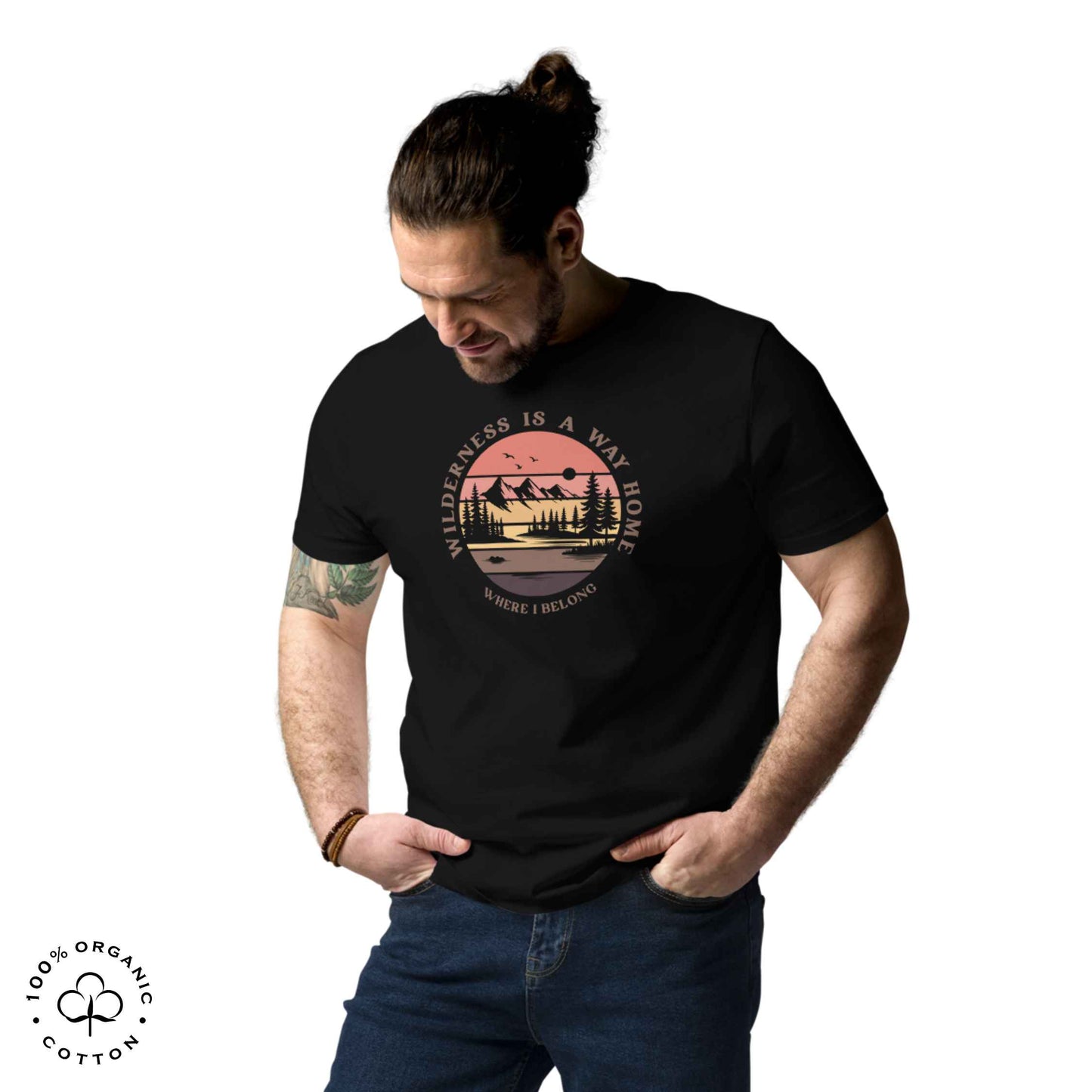 Man wearing eco-friendly t-shirt in organic cotton, black with graphic featuring a nature theme: mountains, trees, sun and the bold phrase “wild nature is the way home, where I belong”.