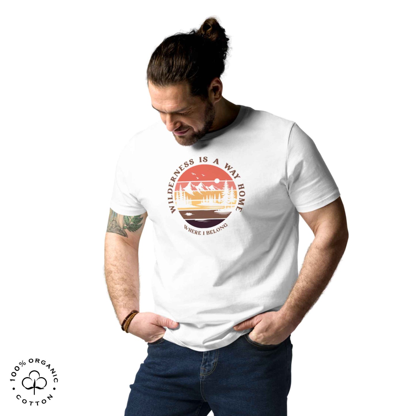 Man wearing Eco-friendly t-shirt in organic cotton, white, with graphic featuring a nature theme: mountains, trees, sun and the bold phrase “wild nature is the way home, where I belong”.