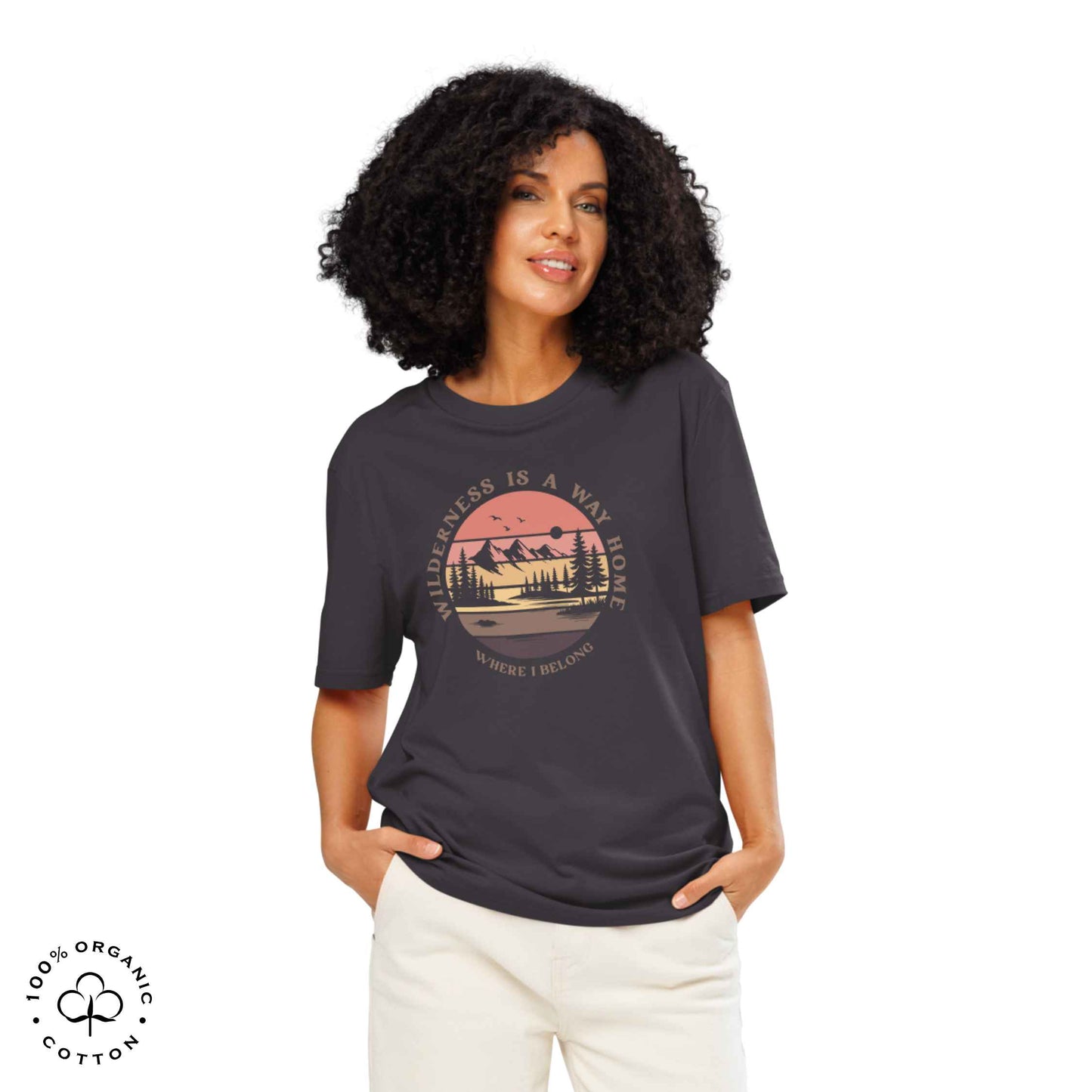 Woman wearing Eco-friendly t-shirt in organic cotton, anthracite, with graphic featuring a nature theme: mountains, trees, sun and the bold phrase “wild nature is the way home, where I belong”.
