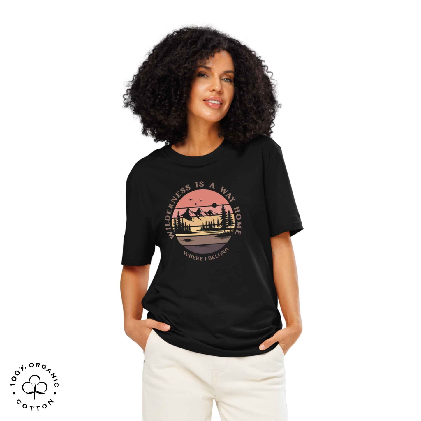 Woman wearing Eco-friendly t-shirt in organic cotton, black, with graphic featuring a nature theme: mountains, trees, sun and the bold phrase “wild nature is the way home, where I belong”.