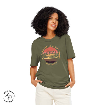Woman wearing Eco-friendly t-shirt in organic cotton, khaki, with graphic featuring a nature theme: mountains, trees, sun and the bold phrase “wild nature is the way home, where I belong”.