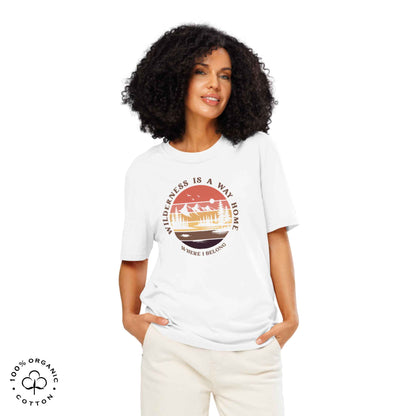 Woman wearing Eco-friendly t-shirt in organic cotton, white, with graphic featuring a nature theme: mountains, trees, sun and the bold phrase “wild nature is the way home, where I belong”.